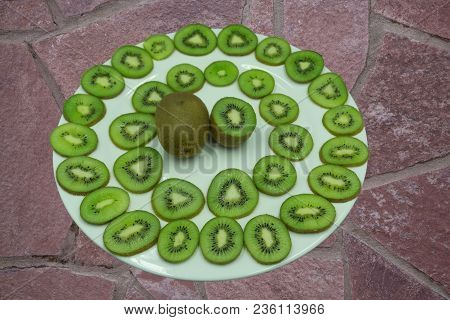 Cut Pieces Of Green Kiwi In The Peel Lying On Wooden Cutting Board