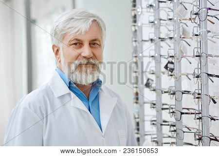 Frontview Of Expirienced Oculist Staing In Gront Of Stand With Glasses, Made For Vision Protection A