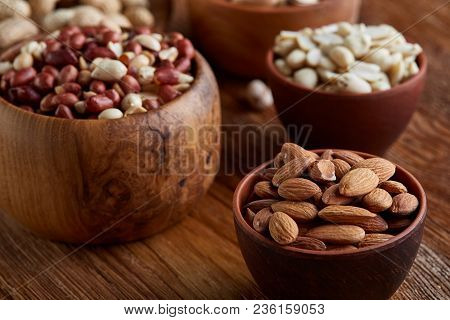 A Composition From Different Varieties Of Nuts In A Wooden Bowls Over Rustic Background: Hazelnuts, 