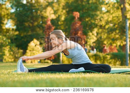 Girl Doing Stretching On The Park's Grass.