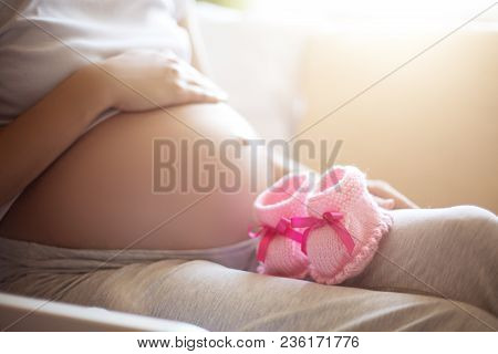 Pregnant Woman Belly Holding Pink Baby Booties, Expecting Girl. Healthy Pregnancy.