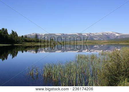 An Icy Lake, Among The Mountains Of Altai. Ulagansky Pass Mountain Tourism Base.