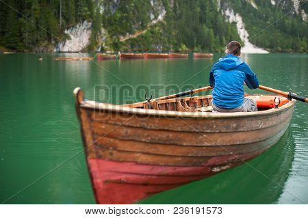 The Guy Is Sitting In A Boat And Starts To Row, Against Lake La-go Di Brize