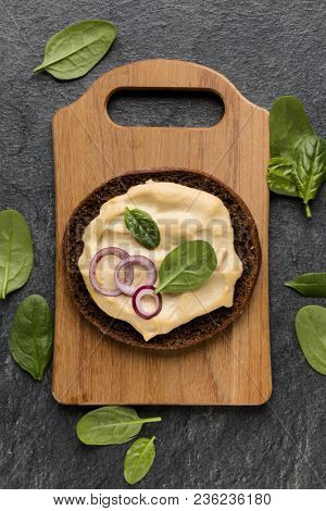 Open faced hummus sandwich canape or crostini on a wooden serving board  on dark stone background closeup. Top view.