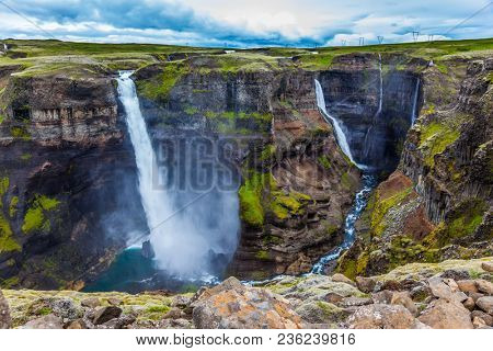  High waterfall Hayfoss in dangerous tundra canyon. The concept of extreme and phototourism. Cloudy and windy summer day in Iceland