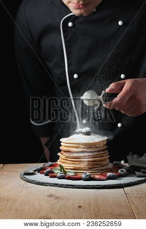 Serving Pancakes With Powdered Sugar And Berries. Chef Man Hand. Beautiful Food Still Life. Slightly