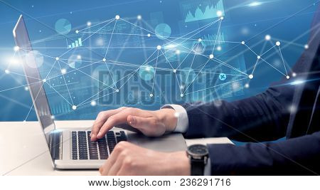 Businessman typing on laptop with linked reports charts grapghs around