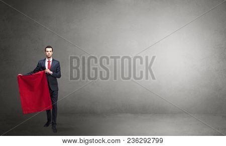 Businessman standing with red toreador cloth in his hand in an empty room