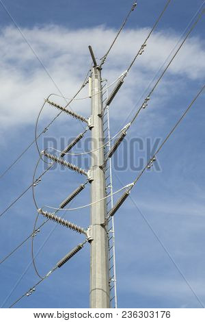 Many High Voltage Power Lines On A Single Mast On A Blue Sky Background