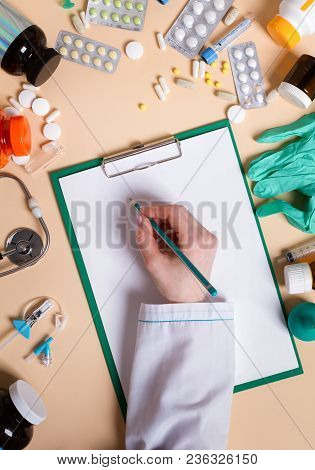 Top View Of Hands Of A Female Doctor Is Writing A Recipe Near Near A Medicine And Medical Staff