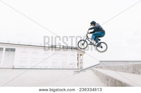 Freestyle On Bmx. A Young Man Jumps On The Bmx From The Stairs Against The Backdrop Of A Minimalisti