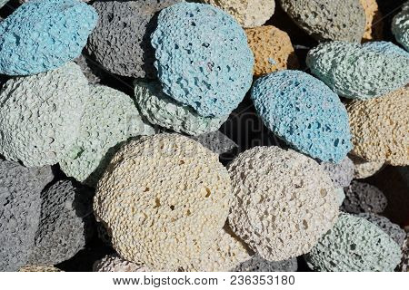 Many Multicolored Porous Pumice Stones Are Next To Each Other.