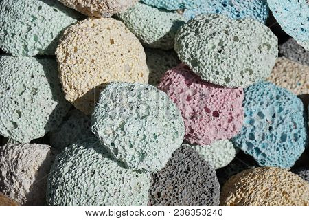 Many Multicolored Porous Pumice Stones Are Next To Each Other.