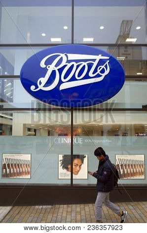 Bracknell, England - April 16, 2018: A Pedestrian Passes By The Window Display Of The Boots Retail S