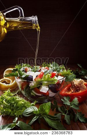 Greek Salad With Olive Oil Pouring From A Bottle And Fresh Vegetables.