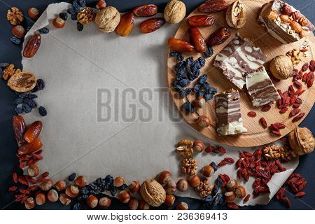 Several Pieces Of Halvah, Nuts And Dried Fruit Food Frame On Paper Background With Copy Space For Te
