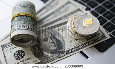 Ethereum Cryptocurrency On Top Of 100 Dollar Biils On A Laptop. Profit From Mining Crypto Currencies