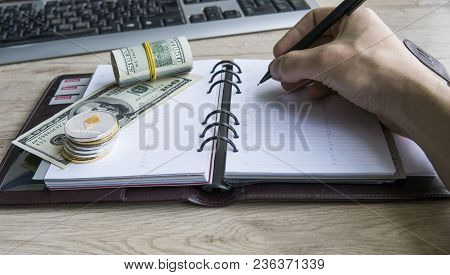 Ethereum Crypto Currency On Top Dollar Biils On Notepad With Mans Hand With Pen. Profit From Mining 
