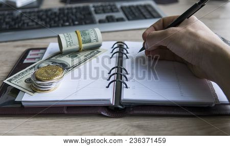 Ethereum Crypto Currency On Top Dollar Biils On Notepad With Mans Hand With Pen. Profit From Mining 