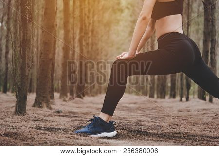 Close Up Of Lower Body Of Woman Doing Yoga And Stretching Legs Before Running In Forest At Outdoors.