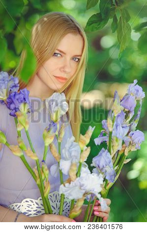Attractive Young Girl With Blonde Dren Hair And Natural Make-up Smelling Blue Purple Iris Flowers On