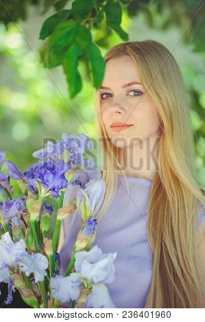 Attractive Young Girl With Blonde Dren Hair And Natural Make-up Smelling Blue Purple Iris Flowers On