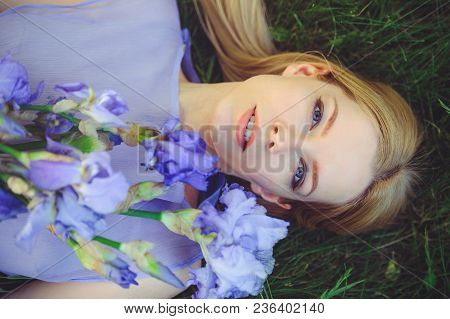 Attractive Young Girl With Blonde Dren Hair And Natural Make-up Smelling Blue Purple Iris Flowers Ly