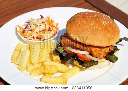A Delicious Crispy Fish Burger With Cheese, Lettuce, And Mayonnaise With French Fries And Salad Onsi