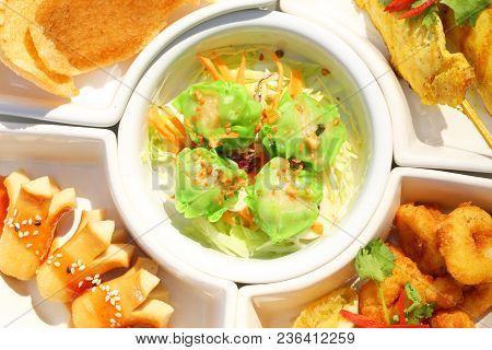 Close Up Mix Delicious Appitizer Set: Dimsum , Sausace, Chicken Satay, Calamari And Rice Cracker On 