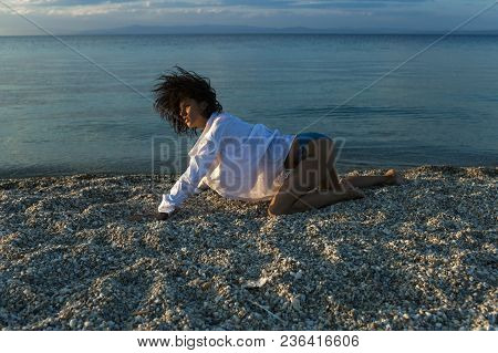 Woman Stands On All Fours, Creeps On Beach In Evening. Girl Sexy, Wears White Shirt And Bikini With 