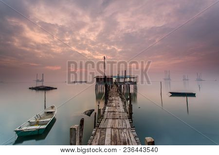Cloudy Long Exposure Sunrise Shot At Jetty. Image Contain Certain Grain Or Noise And Soft Focus When