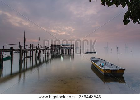 Cloudy Long Exposure Sunrise Shot At Jetty. Image Contain Certain Grain Or Noise And Soft Focus When