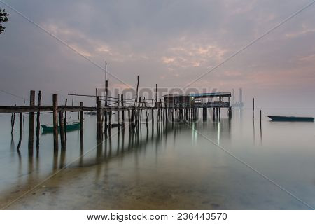 Cloudy Long Exposure Sunrise Shot At Jetty. Image Contain Certain Grain Or Noise And Soft Focus When