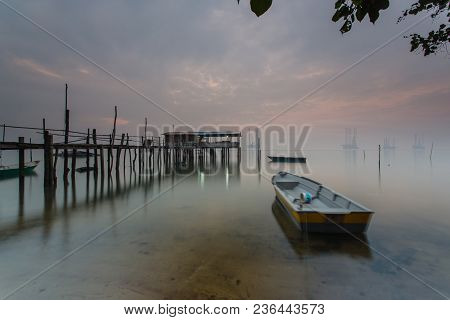 Cloudy Long Exposure Sunrise Shot At Jetty. Image Contain Certain Grain Or Noise And Soft Focus When