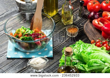 Man Preparing Salad With Fresh Vegetables On A Wooden Table. Cooking Tasty And Healthy Food. On Blac