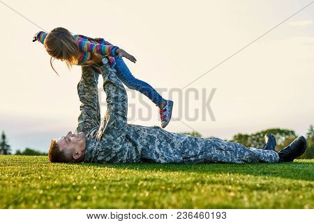 Soldier Lying On The Grass And Playing With Little Girl. Happy Family, Father And Daughter Is Playin