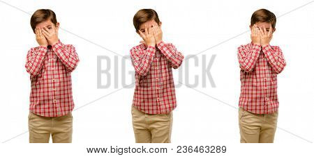 Handsome toddler child with green eyes smiling having shy look peeking through fingers, covering face with hands looking confusedly broadly