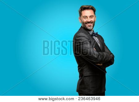 Middle age man, with beard and bow tie with crossed arms confident and happy with a big natural smile laughing