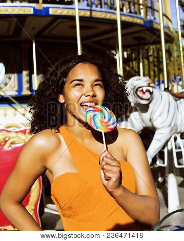 Cool Real Modern Teenage Girl With Candy Near Carousels At Amusement Park Walking, Having Fun