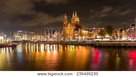 Night City View Of Amsterdam Canal And Basilica Of Saint Nicholas, Holland, Netherlands. Long Panora
