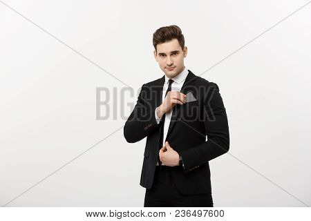 Business Concept: Businessman In Black Suit Picking Pasteboard Or Credit Card Out Of Pocket On Gray 