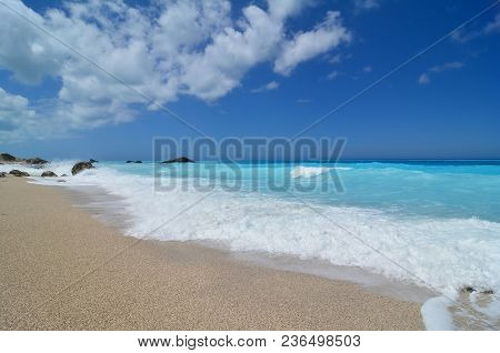 Beautiful Seascape, Idilic Peble Beach, Perfect Turqouise Water, Roling Waves And Blue Sky With Some