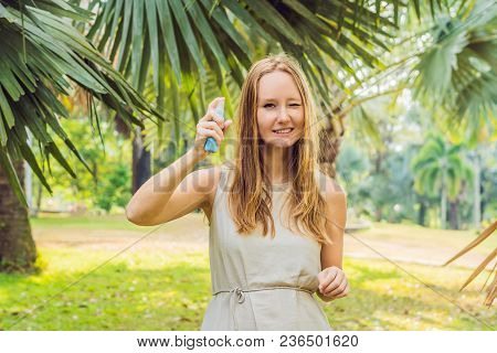 Woman Spraying Insect Repellent On Skin Outdoor.
