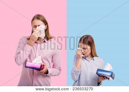 Bitter Tears. Sad Young Couple Crying And Wiping Tears With Tissues While Posing Against Blue And Pi