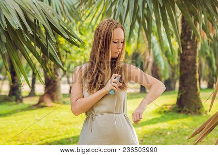 Woman Spraying Insect Repellent On Skin Outdoor.