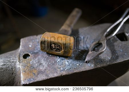 Hammer And Forceps Lie On The Anvil In The Workshop