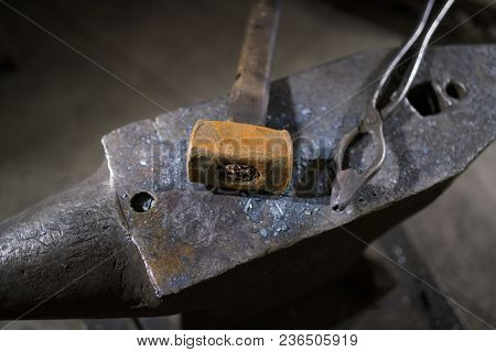 Hammer And Forceps Lie On The Anvil In The Workshop