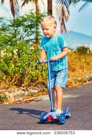 Cute boy riding kick scooter. Child outdoor activity