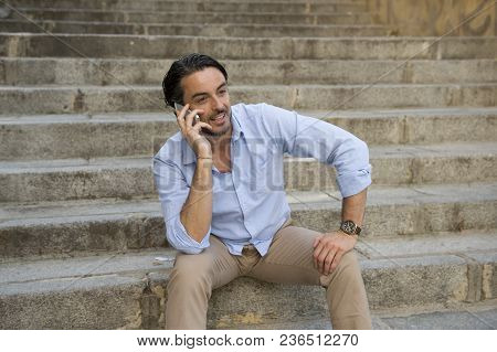 Young Attractive Latin Man On City Staircase Talking Happy On Mobile Phone Looking Satisfied And Con