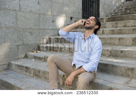 Young Attractive Latin Man On City Staircase Talking Happy On Mobile Phone Looking Satisfied And Con
